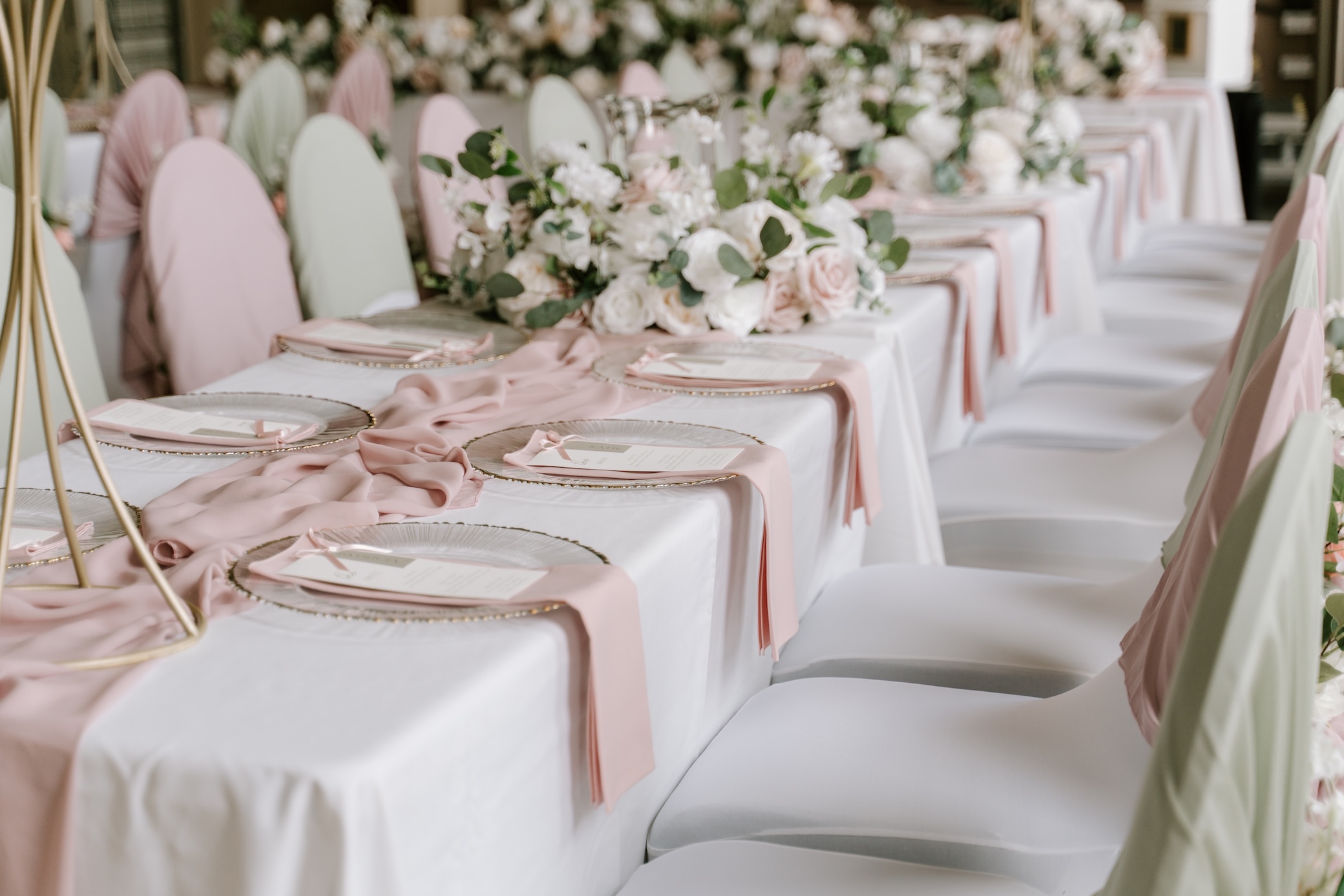 A long wedding breakfast table dressed in white linen with pink runners and floral arrangements
