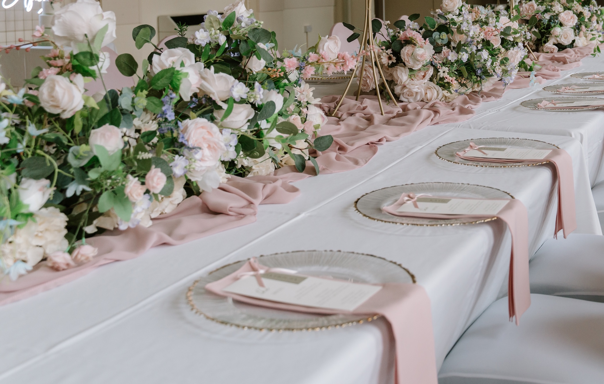 Wedding breakfast place settings with pink napkins and floral table runners